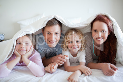 Happy family under bed cover