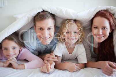 Smiling family under bed cover