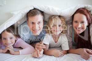 Smiling family under bed cover
