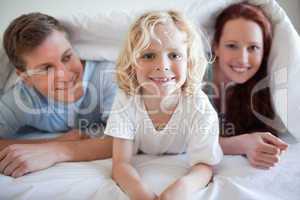 Smiling boy under the cover with his parents