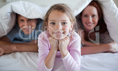 Girl under bed cover with parents