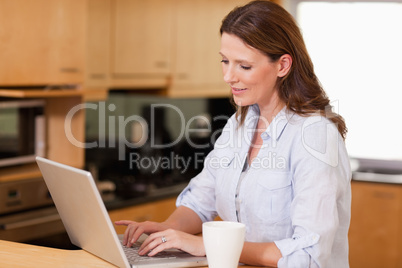 Woman in the kitchen using her laptop