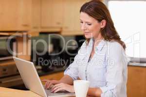 Woman in the kitchen using her laptop