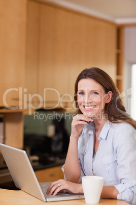 Smiling woman with laptop in the kitchen