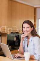 Smiling woman with laptop in the kitchen