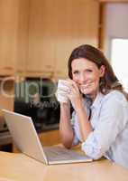 Woman with cup next to laptop