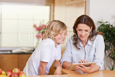 Woman and son using tablet in the kitchen