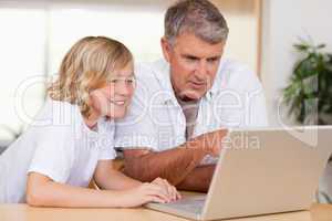 Father and son using laptop in the kitchen