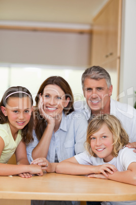 Smiling family behind kitchen table