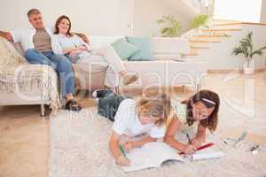 Children doing homework with parents behind them