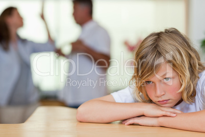 Worried looking boy with fighting parents behind him