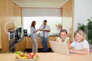 Children with notebook in the kitchen and parents behind them