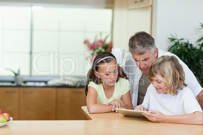 Man looking at tablet his children are using