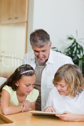 Boy with tablet showing things to sister and father