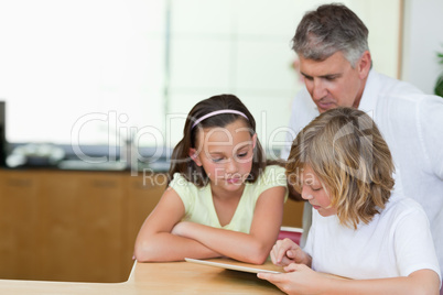 Father together with children and tablet in the kitchen