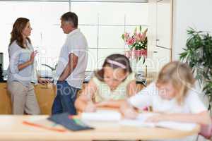 Parents talking with children doing homework in front of them