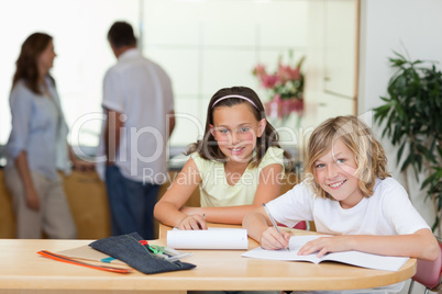 Siblings doing homework with their parents behind them