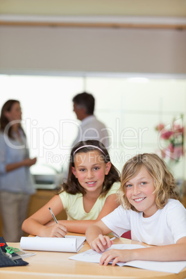 Children doing homework with their parents behind them