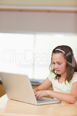 Girl typing on laptop in the kitchen