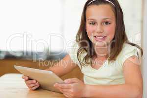 Girl sitting at kitchen table with tablet