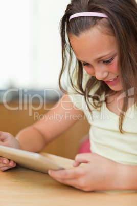 Girl sitting at kitchen table while looking at tablet