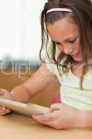 Girl sitting at kitchen table while looking at tablet