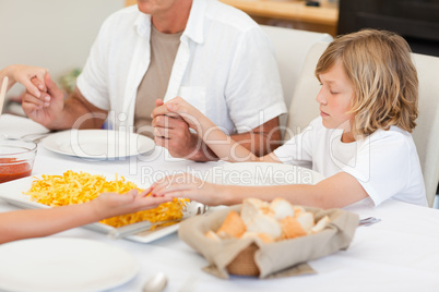 Family saying a prayer before dinner