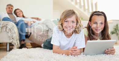 Siblings with tablet on the carpet