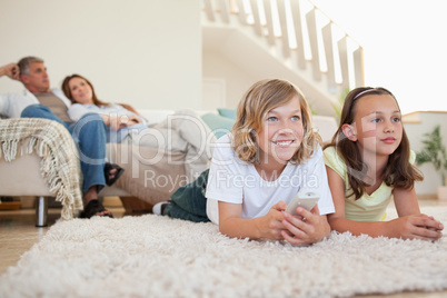 Siblings lying on the carpet watching tv