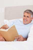 Smiling man reading in bed