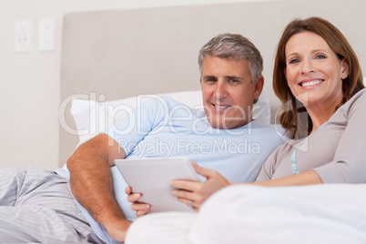 Couple with tablet in bed