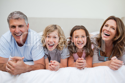 Laughing family lying on the bed