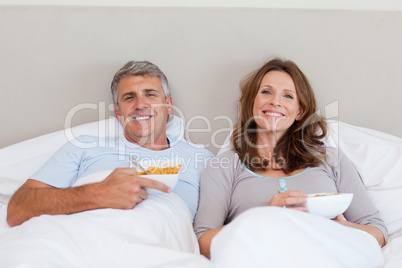 Couple eating cereals in bed
