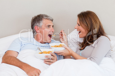 Mature couple eating cereals in bed