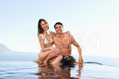 Happy couple sitting on pool edge