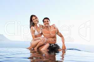 Happy couple sitting on pool edge