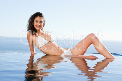 Woman enjoys sunbathing on pool edge