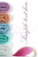 multicolor towels stacked with a lotus petal on white background