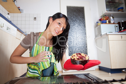 Frau mit einem Kuchen aus dem Inneren eines Ofens
