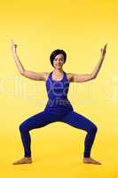 Young woman in blue doing yoga asana on yellow
