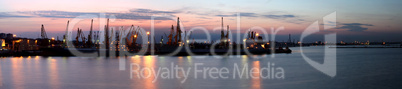 Silhouette of several cranes in a harbor, shot during sunset