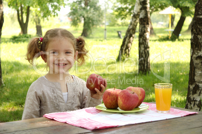 little girl with apple and juice in park