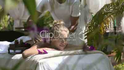 Happy young woman smiling during massage in spa