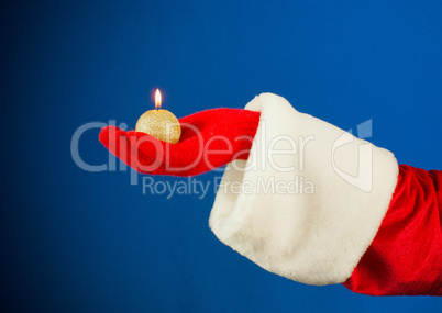 Santa's hand holding a burning candle over blue background