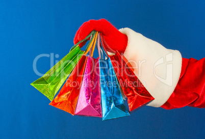 Santa's hand holding colorful bags