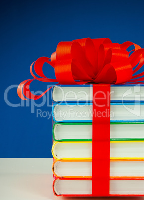 Stack of colorful books tied up with red ribbon