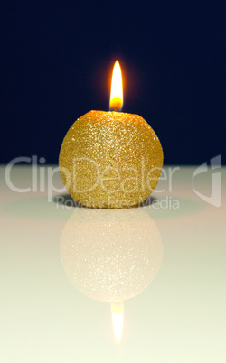 Golden burning candle against blue background