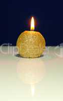 Golden burning candle against blue background
