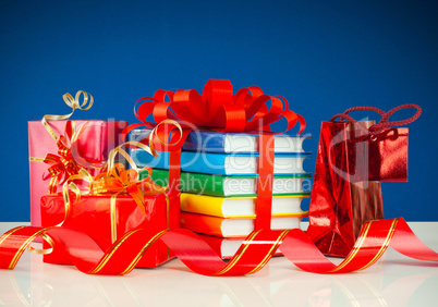 Christmas presents with stack of books against blue background