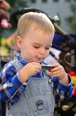 Kleiner Junge untersucht eine Mundharmonika